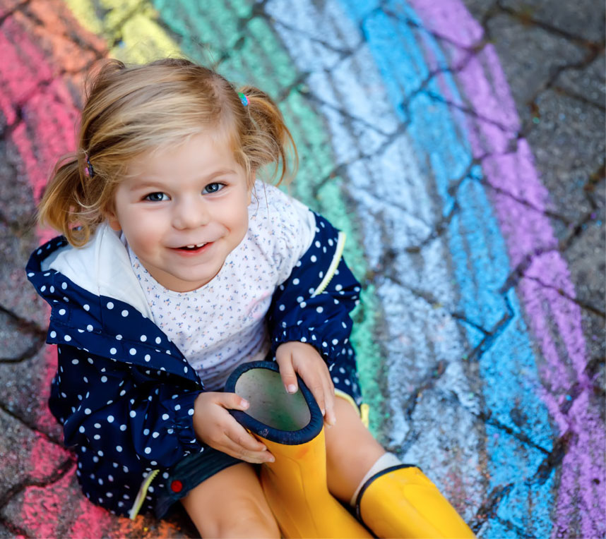 child sitting on chalk rainbow