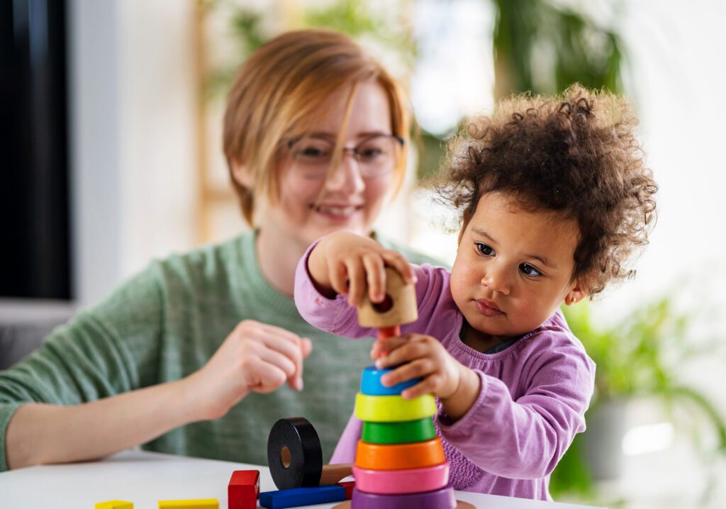 teacher and child play with colorful ring toys