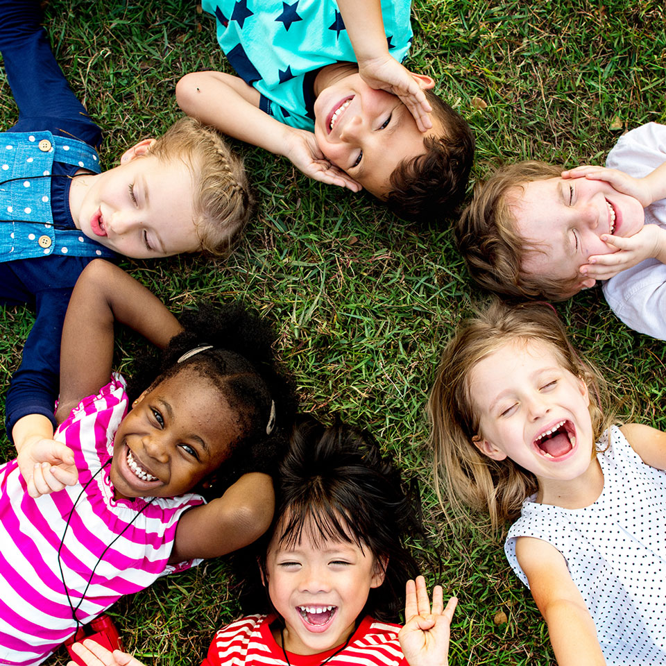 Group of kindergarten kids lying on the grass at park and relax