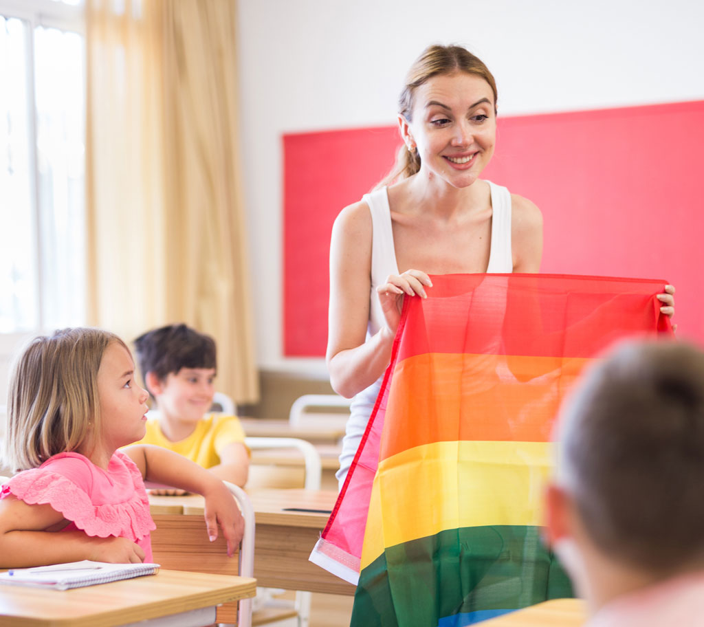 teacher in classroom holding pride flag