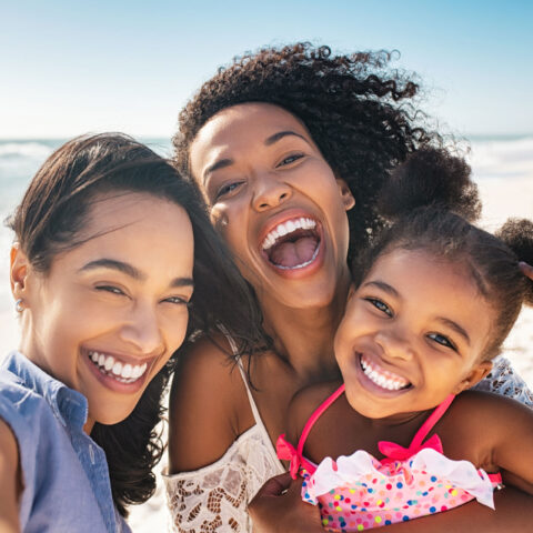 happy parents and child selfie at the beach