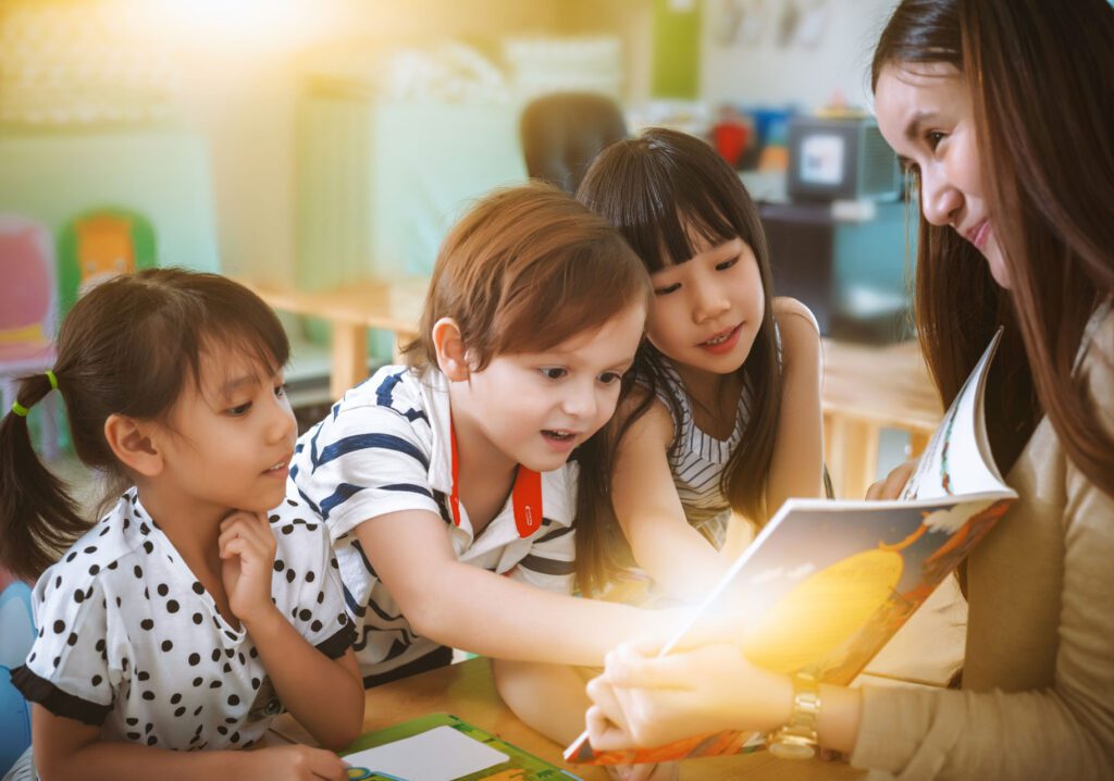 three children and teacher reading book