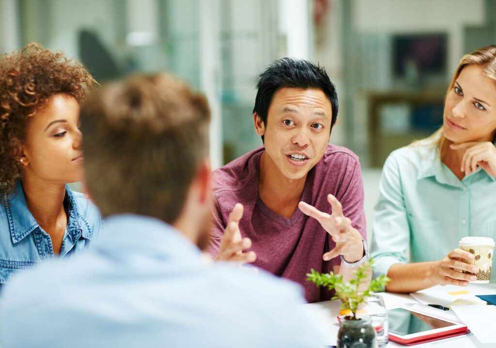 Shot of a group of people talking together around a table in an office