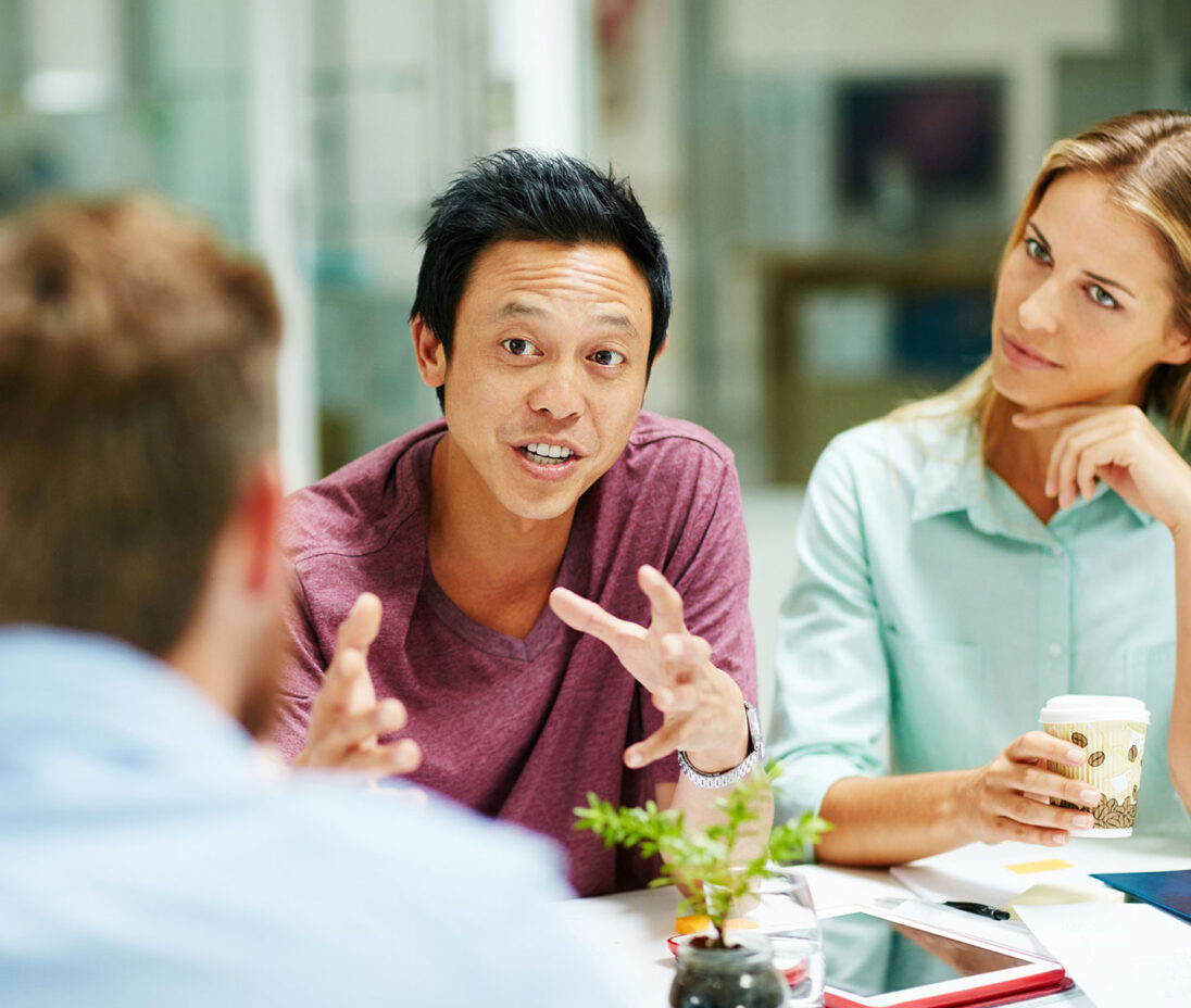 Shot of a group of people talking together around a table in an office