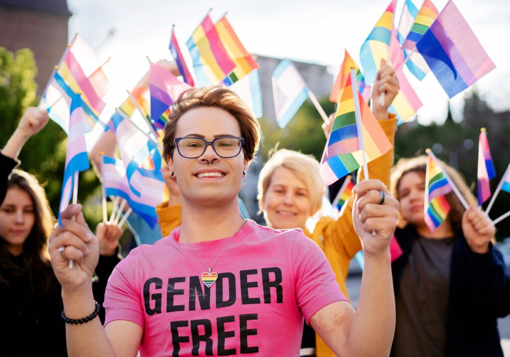 Activists holding different LGBTQ+ flags and defending the rights of the LGBTQ+ community