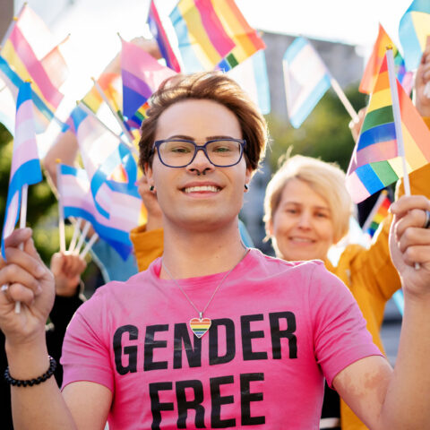 Activists holding different LGBTQ+ flags and defending the rights of the LGBTQ+ community