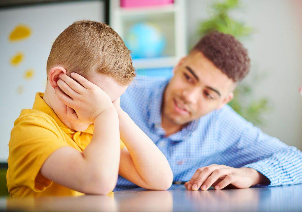 teacher with child covering face with hands