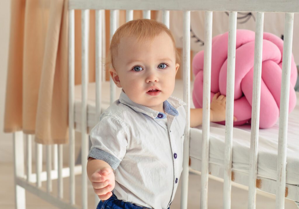 child standing next to crib